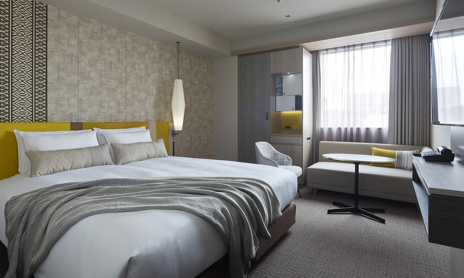 The Superior , 1 bed King room features a king-sized bed with a gray throw, a comfortable sofa with a round table, and modern decor.