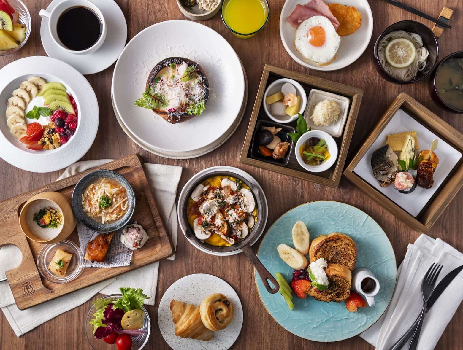 프렌치 토스트, 신선한 과일, 샐러드 등 서양식과 일본식 요리가 모두 포함된 다양한 아침 식사가 우드 테이블 위에 놓여 있는 모습.