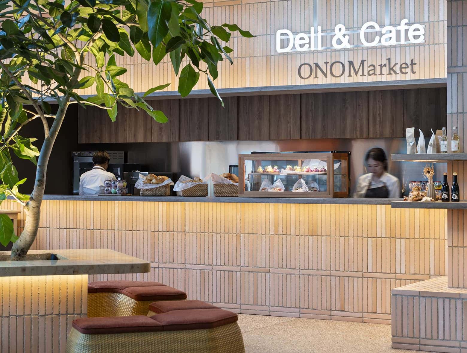 세련된 호텔 카페 카운터, ‘Deli & Cafe ONO Market’라는 간판과 페이스트리 진열장이 있는 공간.