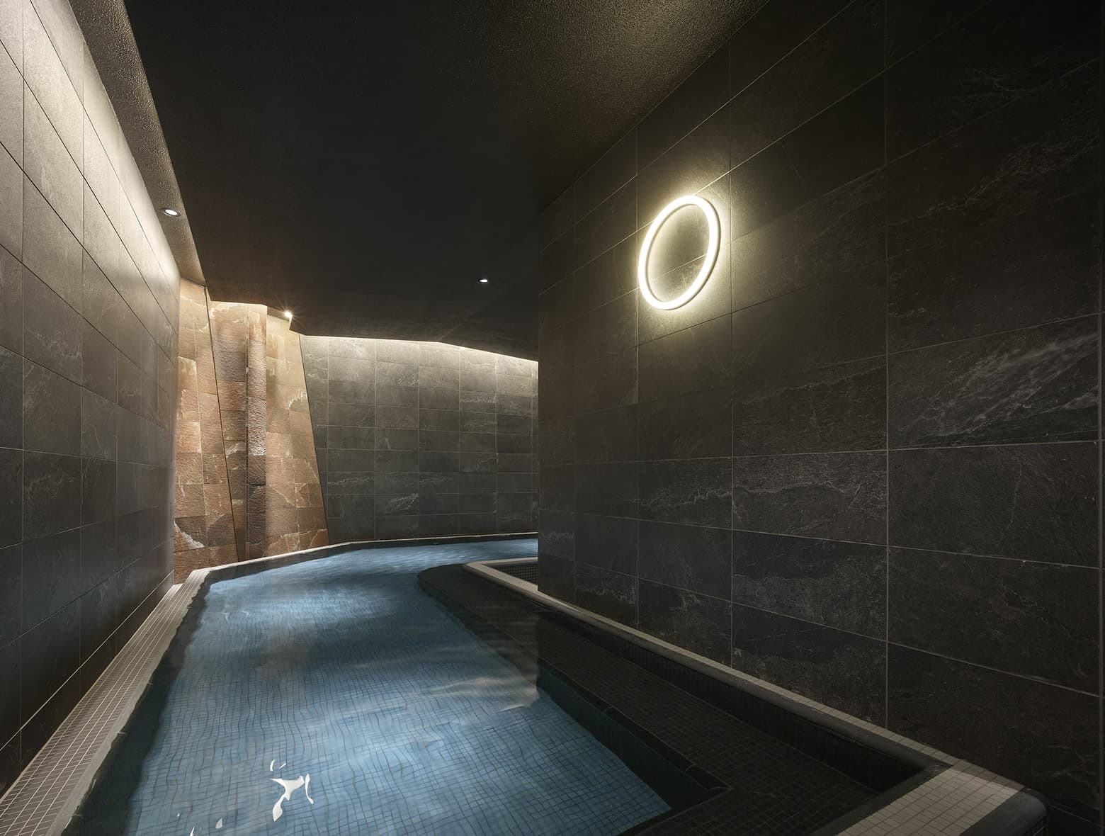좁은 곡선형 욕조, 모던하고 어두운 타일 벽, 따뜻한 포인트 조명이 있는 은은한 분위기의 대욕장.
