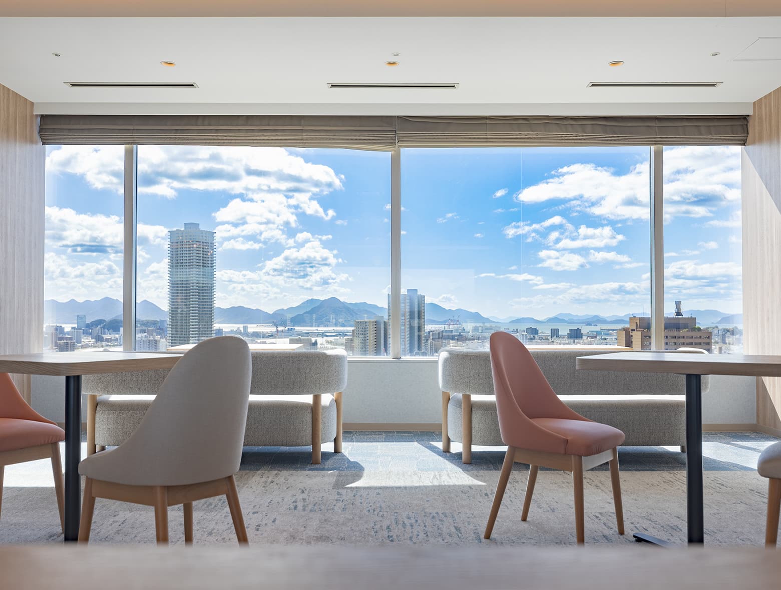 편안한 좌석에서 넓은 창을 통해 탁 트인 도시, 바다, 산 전망을 감상할 수 있는 밝고 넓은 최상층 라운지.