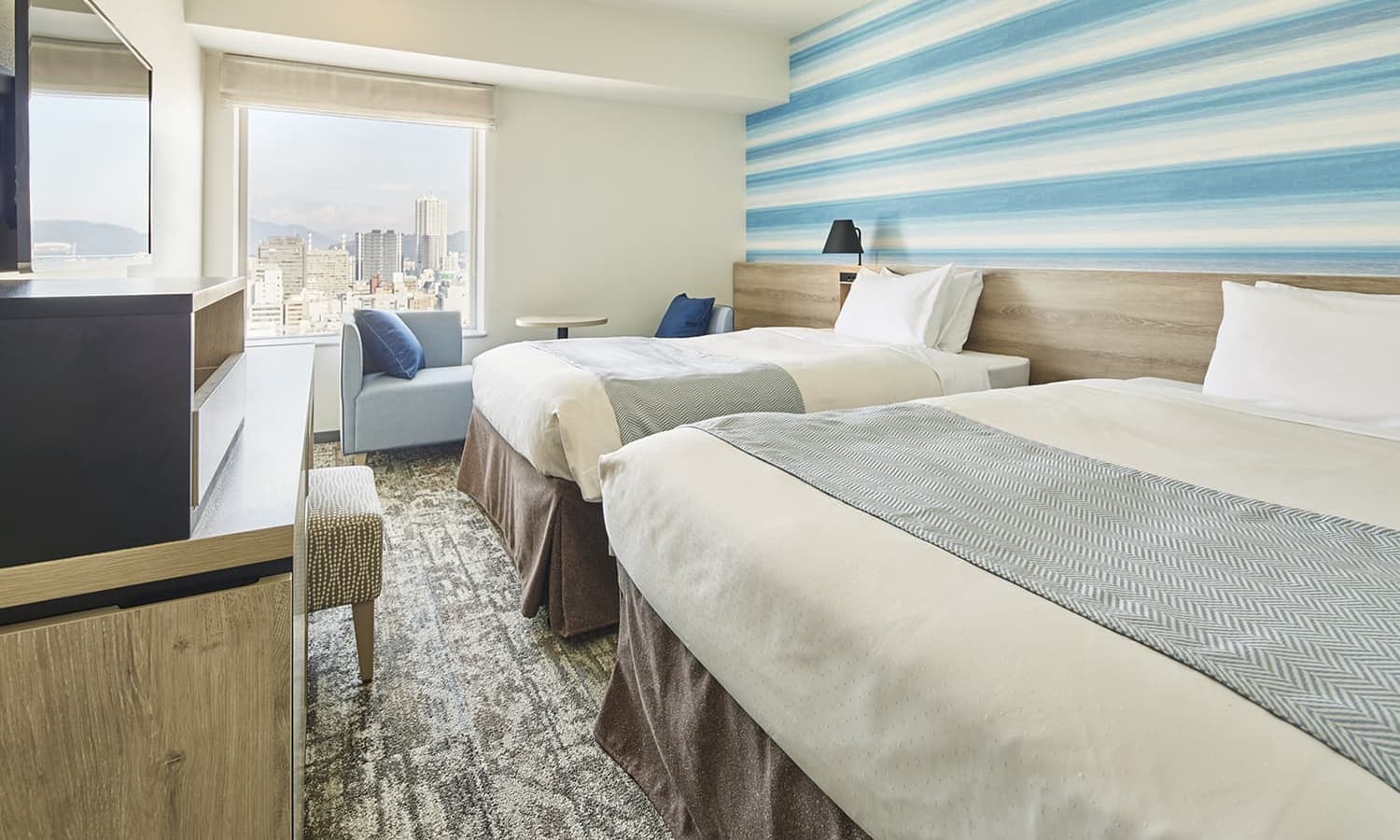 슈페리어 트윈룸에는 싱글 침대 두 개, 카펫 바닥, 우드 소재 헤드보드, 패턴 벽지, 좌석 공간, 탁 트인 도시 전망을 감상할 수 있는 넓은 창이 있습니다.