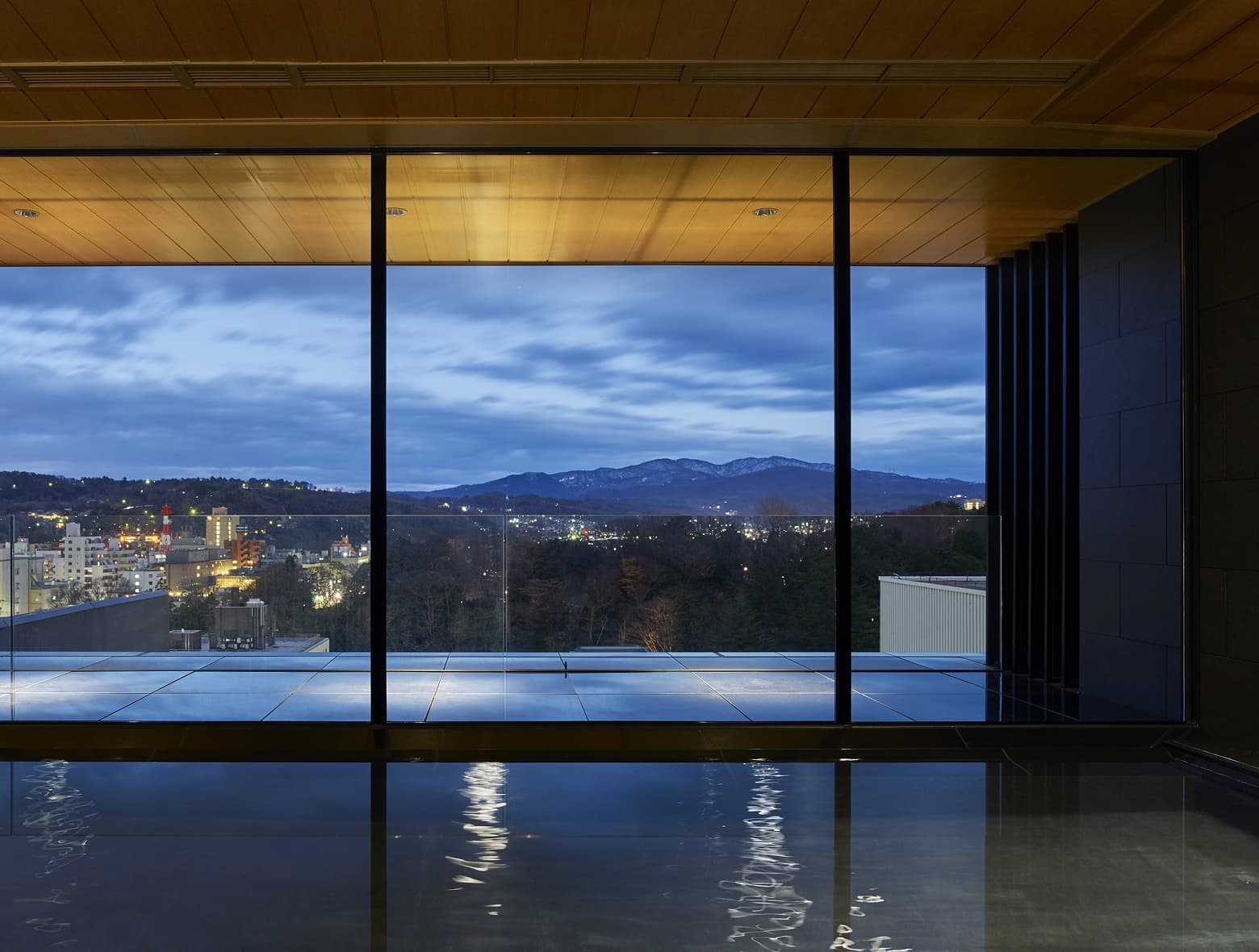 탁 트인 창문을 통해 저녁 산과 도시의 풍경을 감상할 수 있는 실내 대욕장.
