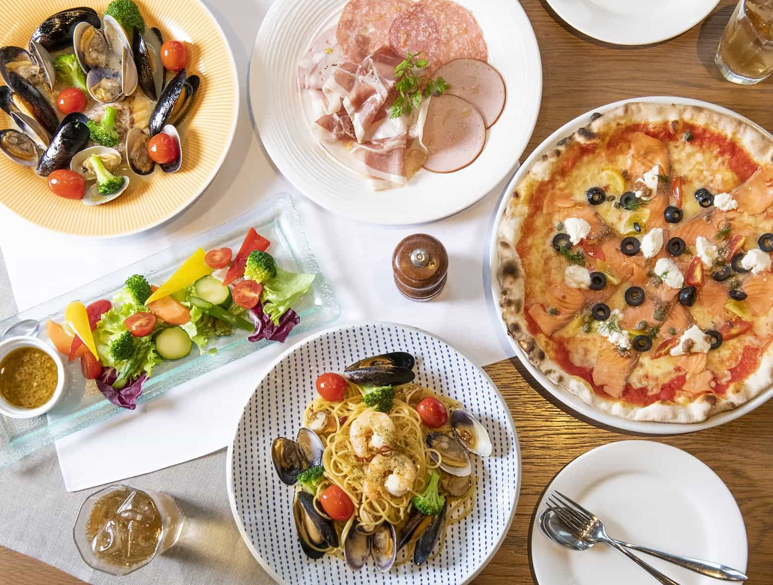 피자, 홍합 파스타, 숙성육, 바냐 카우다 등 이탈리아풍 디너 메뉴를 위에서 본 모습.
