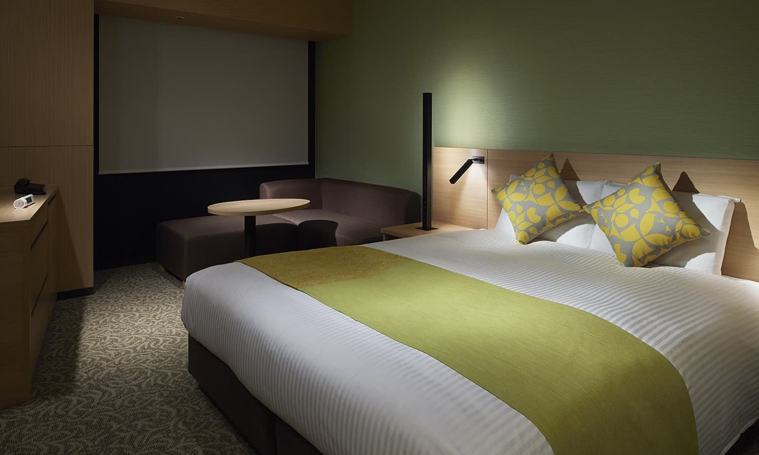 스탠다드 퀸룸(3~6층)은 퀸 사이즈 침대, 올리브 그린 색상의 포인트 장식, 그리고 코너에 놓인 작은 코너형 소파가 있는 아늑하고 현대적인 호텔 객실입니다.