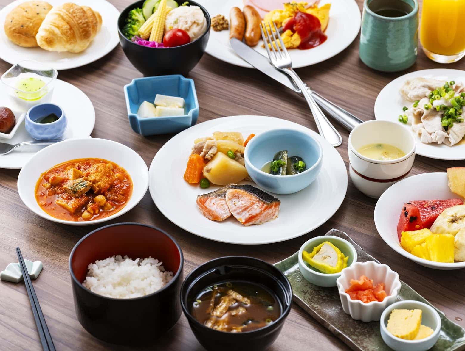 연어 구이, 일본식 된장국, 밥, 빵, 신선한 과일 등 다양한 일본식 및 서양식 아침 식사 메뉴.