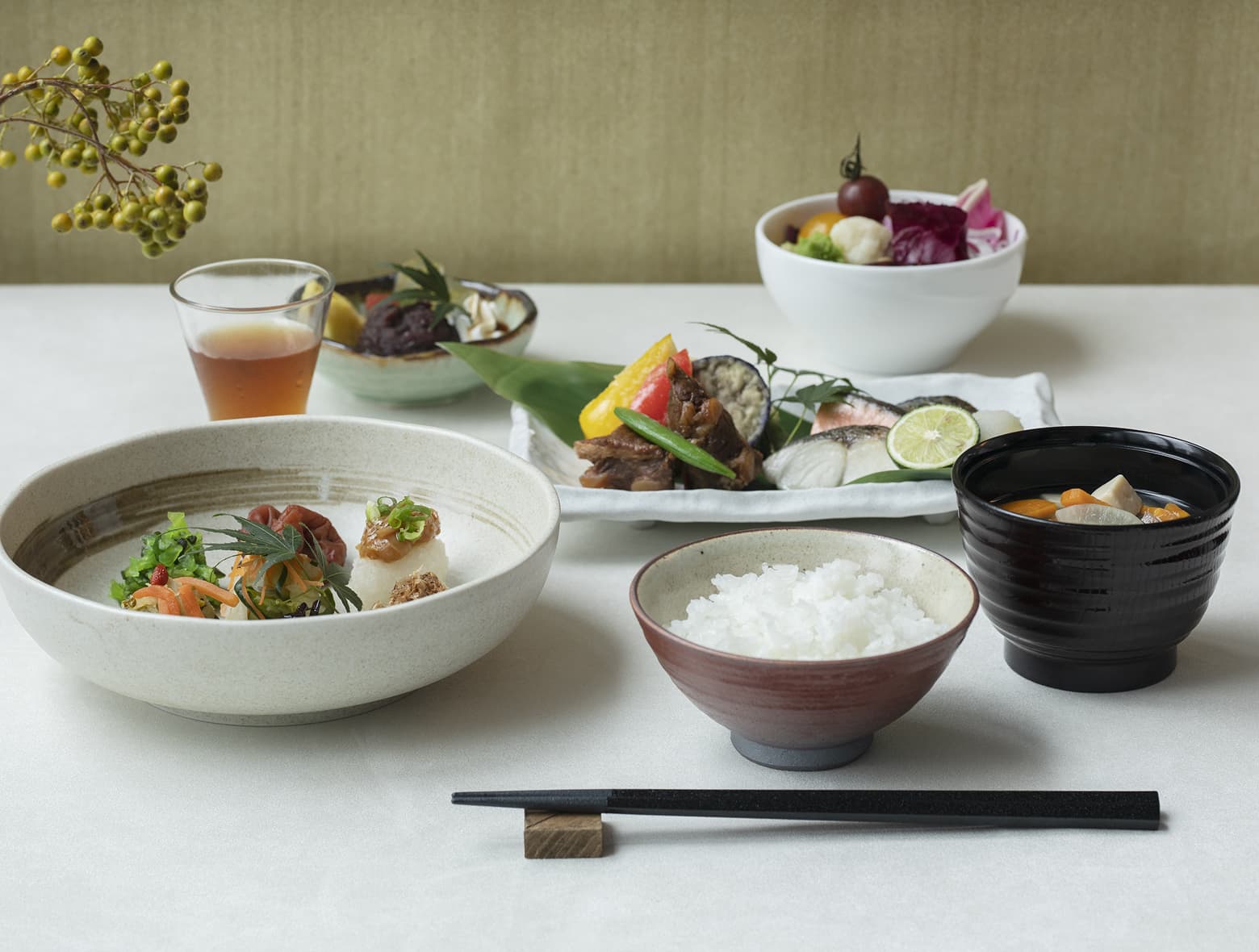 밥, 미소시루(일본식 된장국), 구운 생선, 다양한 반찬, 차로 구성된 일본식 식사가 흰 식탁보 위에 아름답게 차려진 모습.