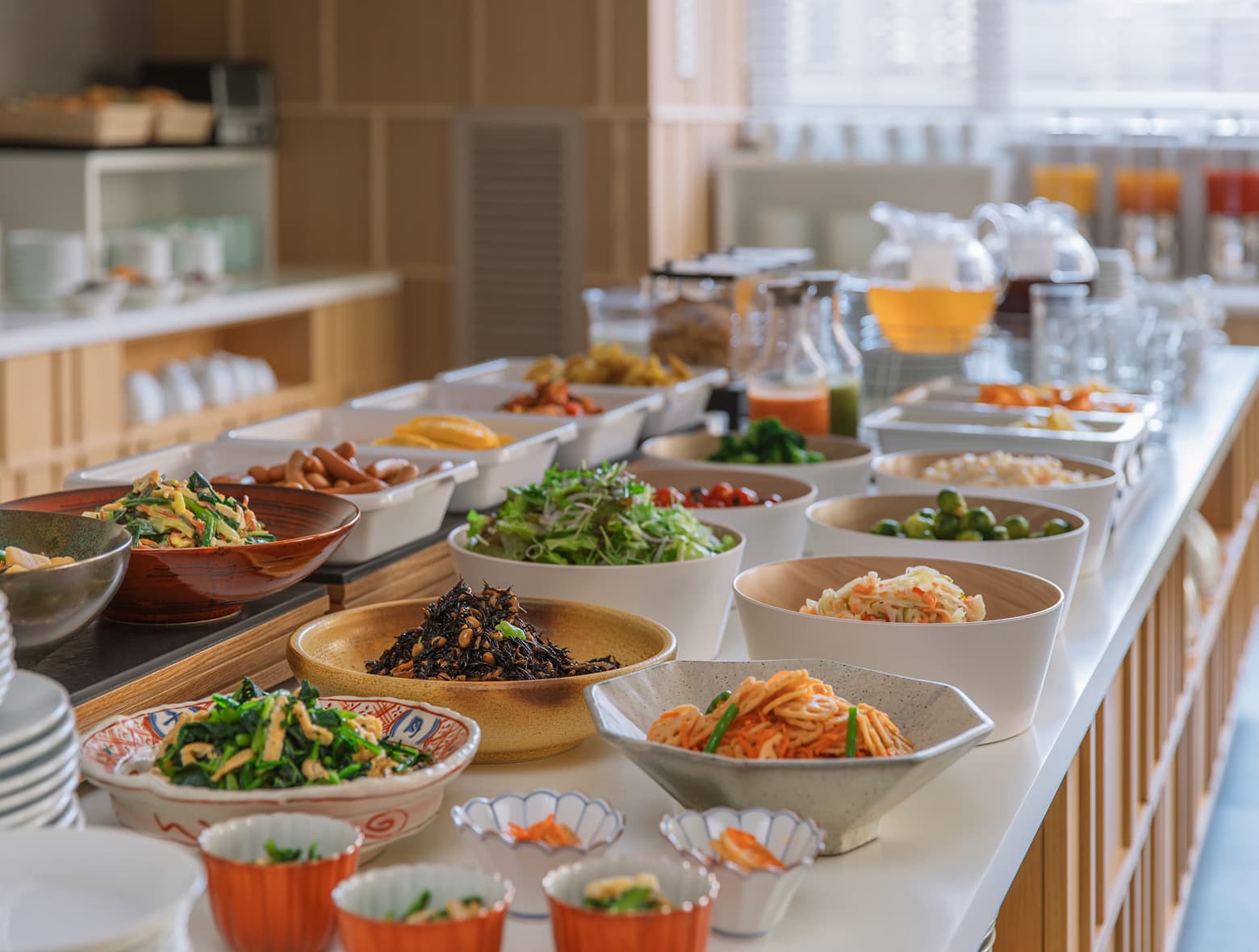 신선한 샐러드를 포함한 다양한 건강식 반찬과 일식, 양식 요리가 제공되는 호텔 조식 뷔페 카운터.
