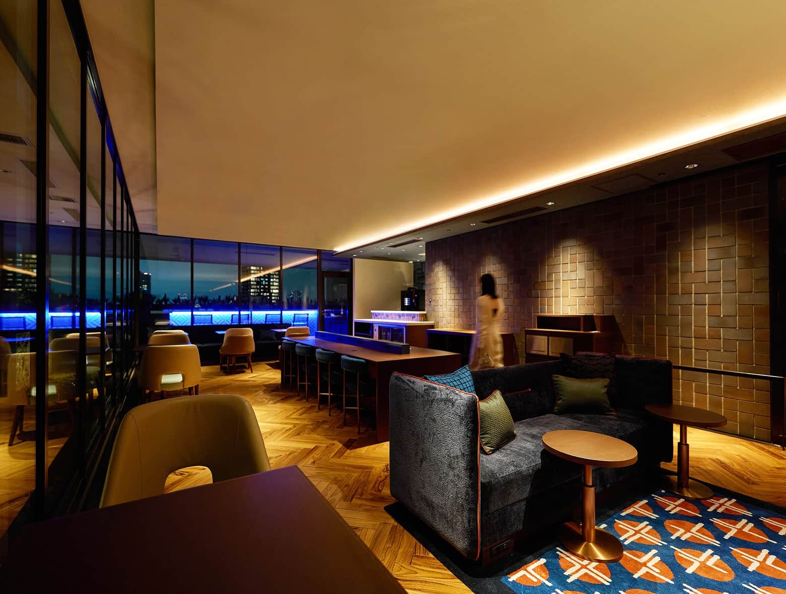 Our 16th-floor lounge features panoramic city views through large windows, luxury wooden floors, ambient tile walls, and comfortable seating.
