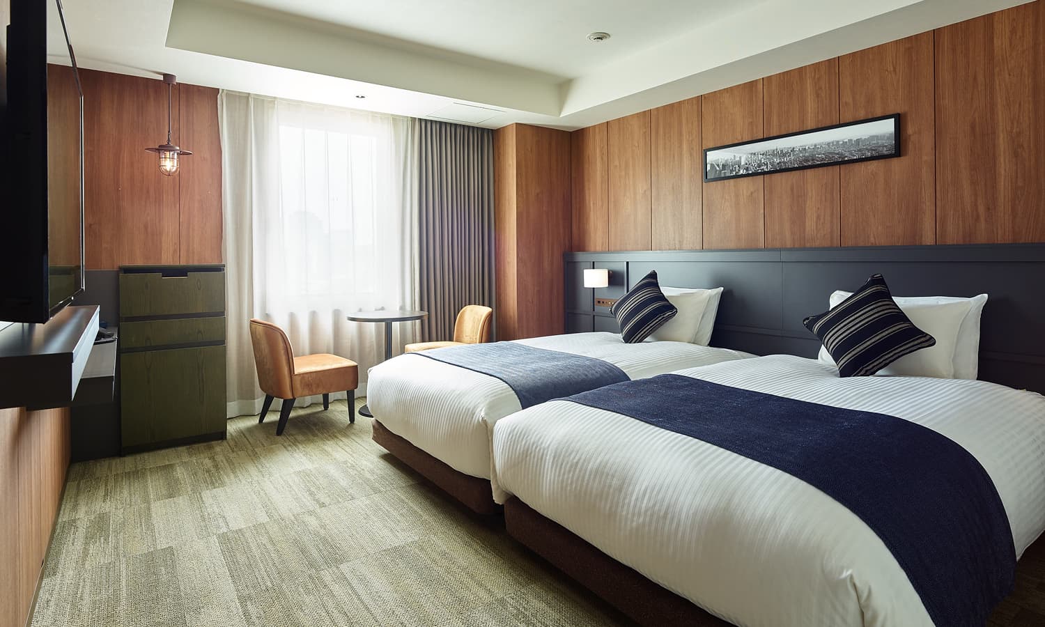 高级双床房配有两张床、木质镶板、一张带椅子的小桌和一台壁挂式电视。