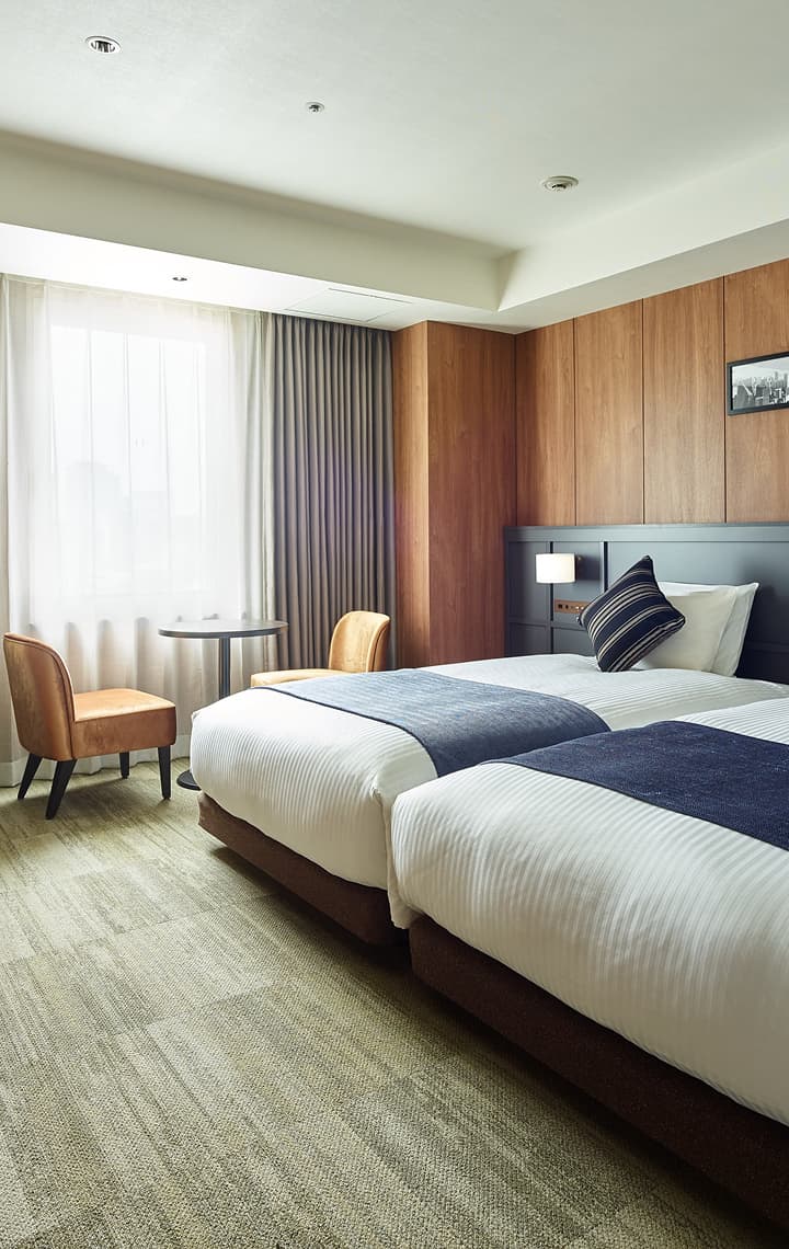 高级双床房配有两张床、木质镶板、一张带椅子的小桌和一台壁挂式电视。