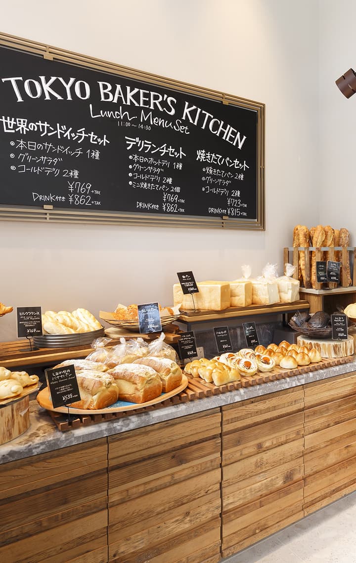 面包柜台上摆放着各种新鲜的面包、糕点和三明治，墙上挂着菜单。