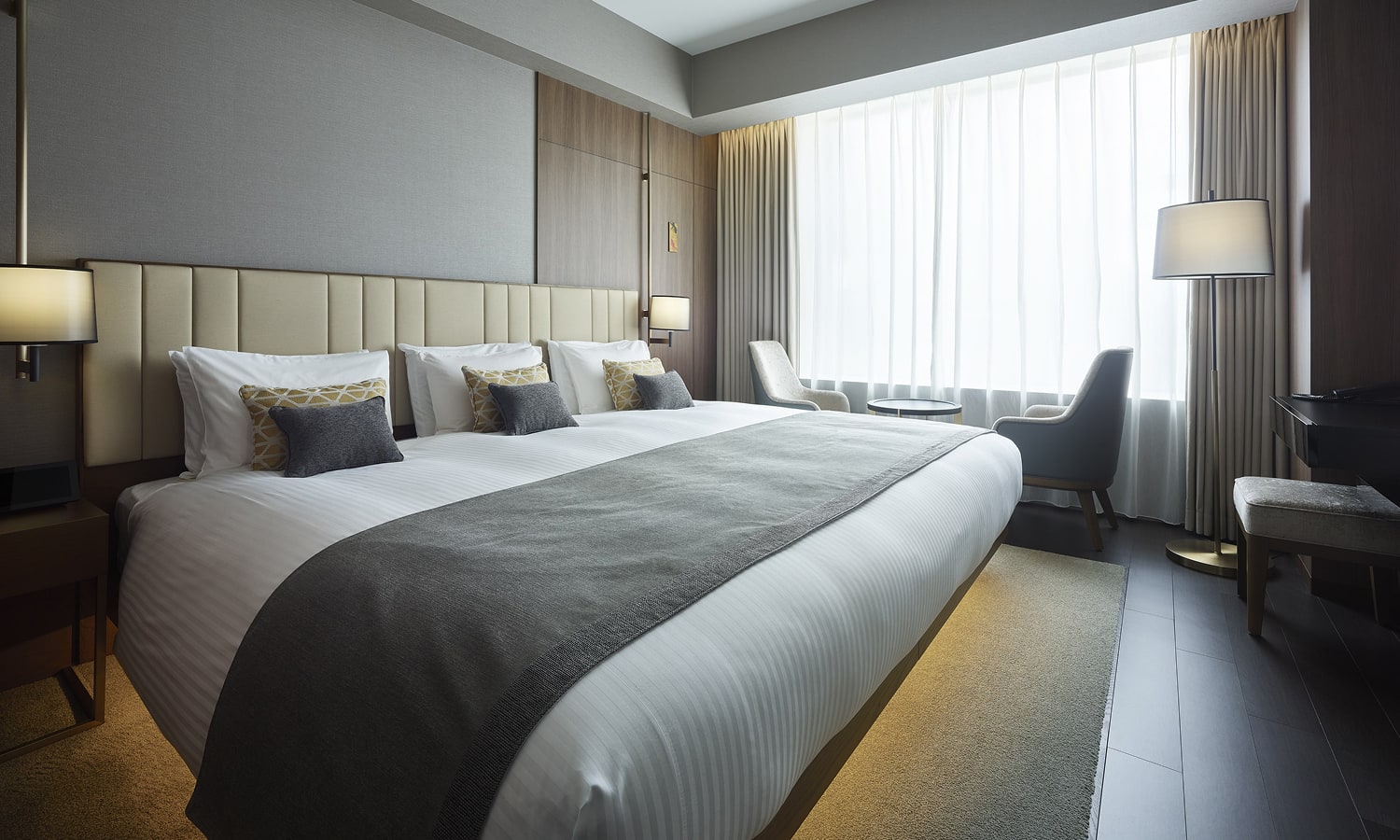 The Superior , 1 bed WideKing room includes an extra wide king bed with a padded headboard, and a seating area next to a large window for natural light.