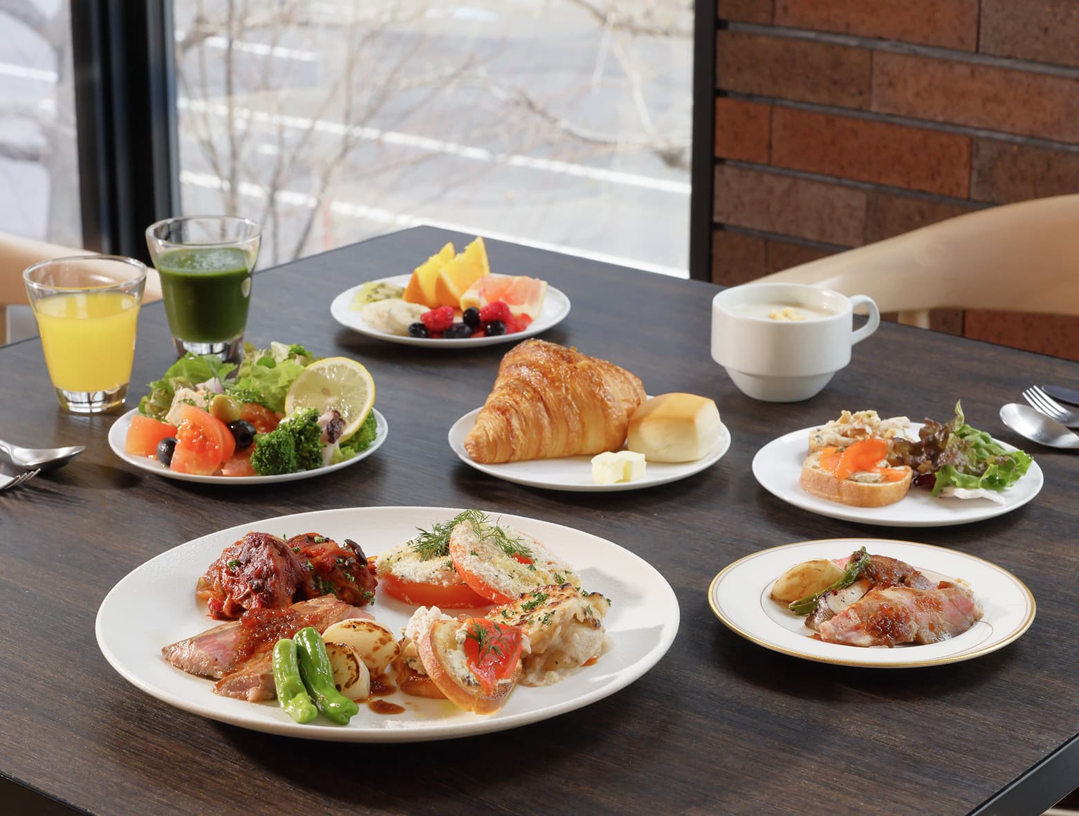 WEST Table의 식탁에 고기, 샐러드, 크루아상, 신선한 과일, 수프, 주스 등 맛있는 음식이 차려진 모습.