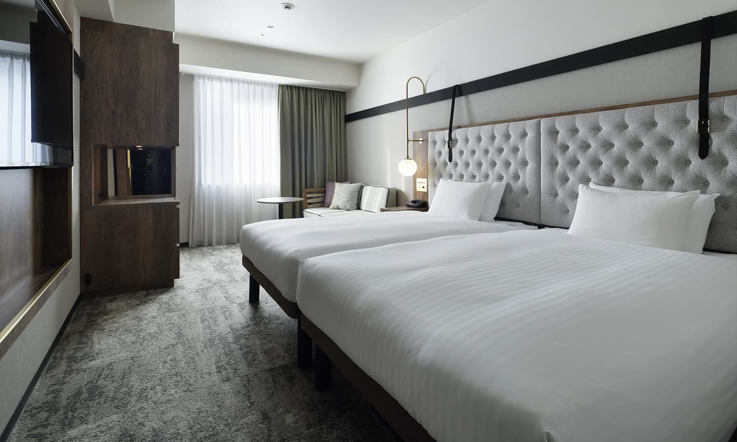 슈페리어 트윈(+소파베드, 욕조)룸에는 회색 퀼팅 헤드보드가 있는 트윈 침대, 소파베드, 어두운 색 목재 장식, 벽걸이 TV, 넓은 창이 있습니다.