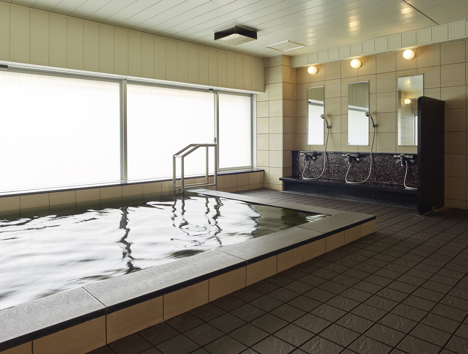 寧靜的大浴場有一個寬敞的長形浴池、一整排淋浴間和一扇明亮的窗戶。