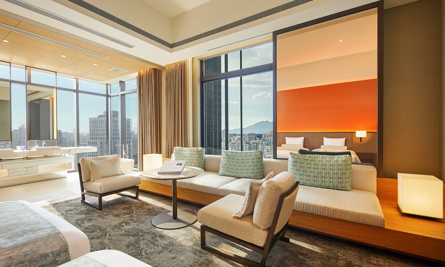 주니어 스위트룸에는 트윈 침대, 커다란 베이지색 코너 소파, 대리석 테이블, 도시 전망을 감상할 수 있는 통창이 있습니다.