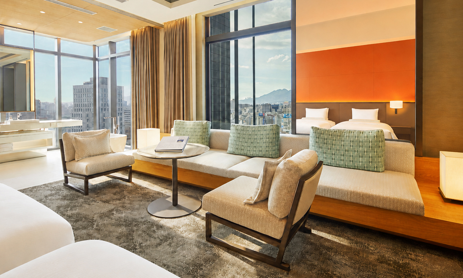 The Junior Suite, 2 beds room features two twin beds, a large beige sectional sofa, marble table, and floor-to-ceiling windows overlooking a city.