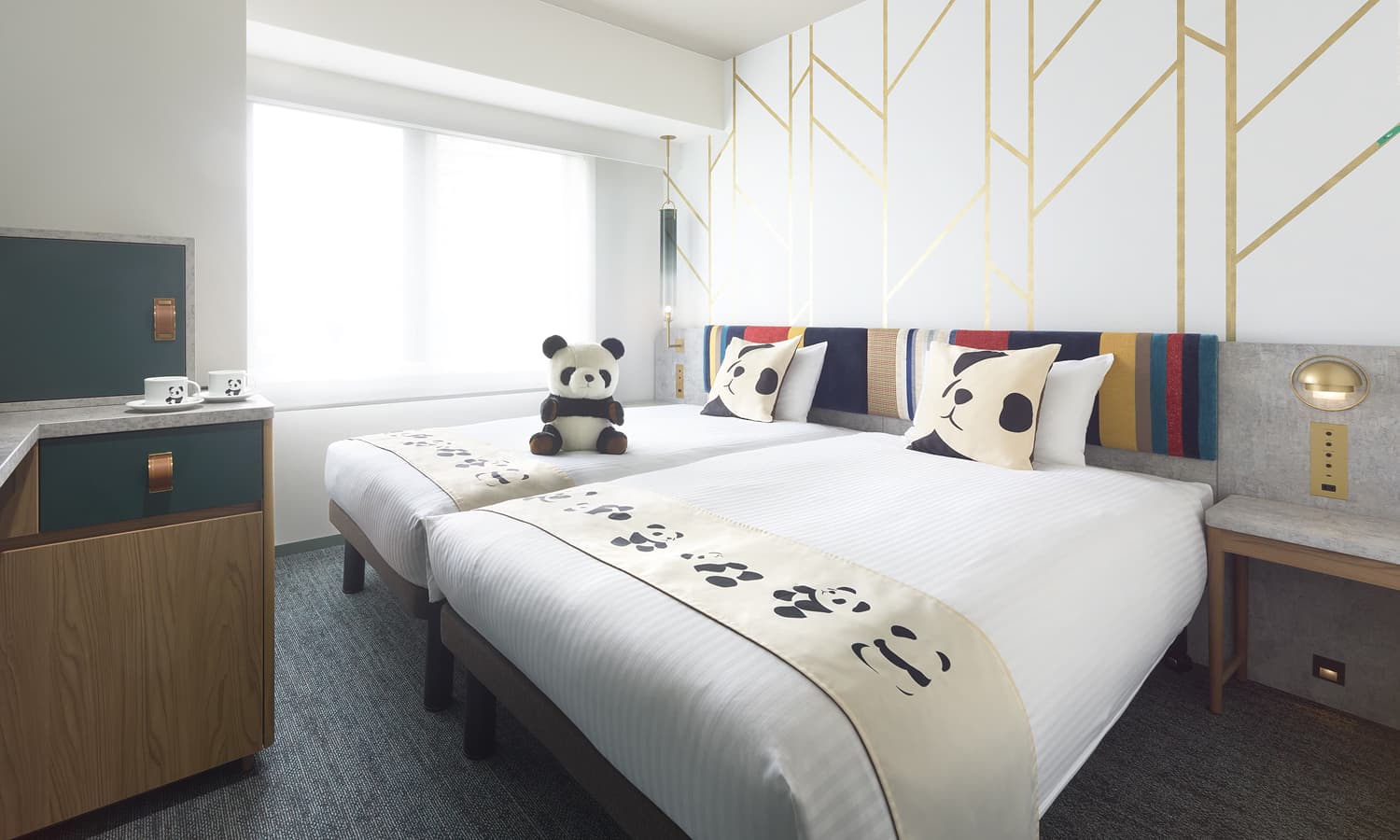 판다 스탠다드 트윈(할리우드 스타일)룸은 싱글 침대 2개, 판다 무늬 침대 러너, 판다 쿠션, 금색 기하학적 패턴이 있는 흰색 벽을 갖추고 있습니다.
