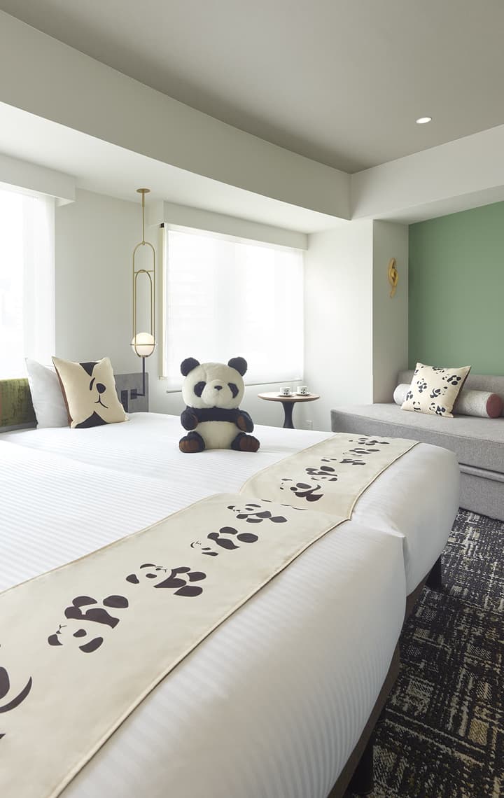 판다 슈페리어 트윈(+소파베드)룸은 싱글 침대 2개, 소파베드, 판다 무늬 쿠션, 판다 무늬 침대 러너, 은은한 녹색 포인트 벽을 갖추고 있습니다.