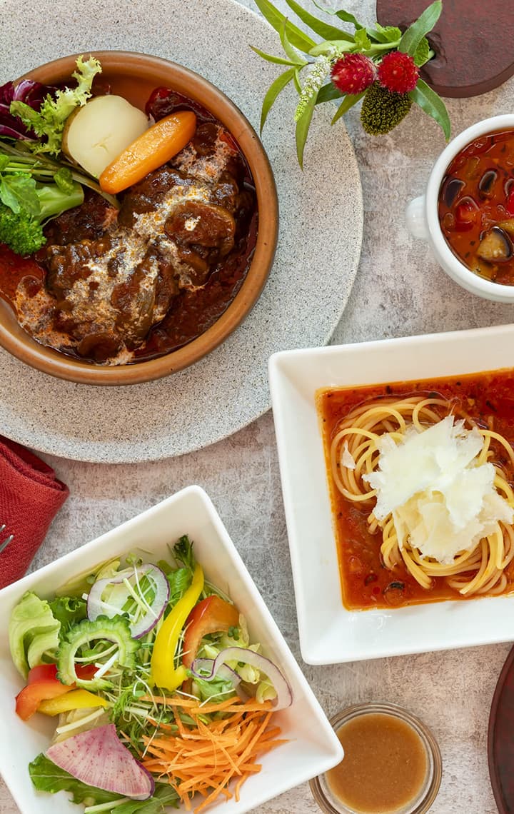 흰색 정사각형 접시에 담긴 파스타, 베이커리류, 샐러드, 햄, 수프 등 다양한 뷔페 음식을 위에서 바라본 모습.