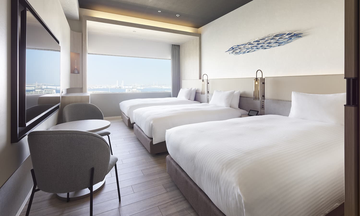 디럭스 트리플룸에는 침대 3개, 도시 전망을 감상할 수 있는 큰 창, 좌석 공간, 벽걸이 TV, 벽 장식이 있습니다.