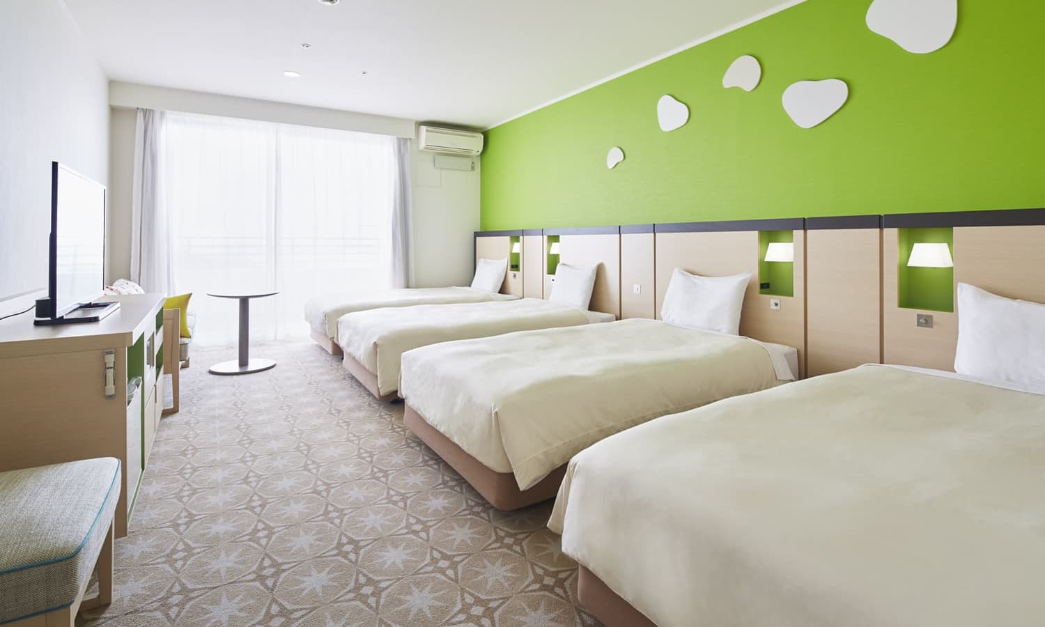 The Deluxe, 4 beds, Balcony room features four single beds, a lime green accent wall, a large window for natural lighting, and a patterned carpet.